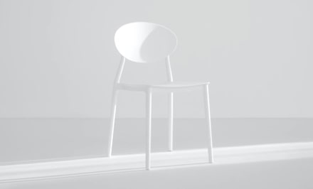 An elegant white chair with white wall background.